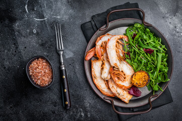 Grilled Jumbo Shrimps Prawns on a plate with salad. black background. top view