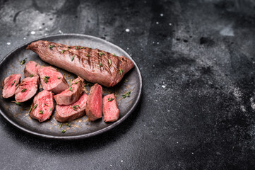 Grilled lamb mutoon sliced steak, tenderloin fillet meat. black background. top view