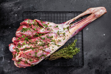 Whole raw lamb mutton leg Marinated with herbs and olive oil. black background. top view