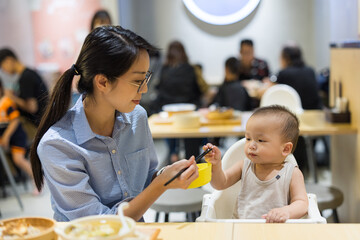 Mother feeding baby boy at restaurant table
