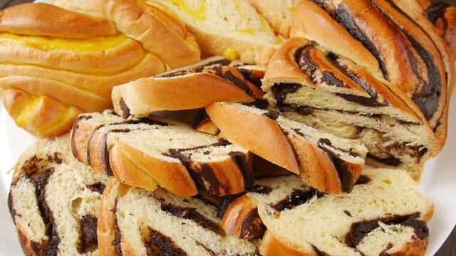 Braided sweet bread with chocolate and custard filling, sliced and arranged on white plates.