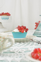 Elegant table decoration with blue and red elements for a wedding, anniversary, birthday or engagement. White tray of cupcakes with red fruits, sweets, cup of tea or coffee.