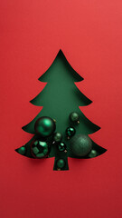 Creative vertical holiday greeting card design featuring a Christmas tree cutout filled with elegant green baubles and ornaments, set against a festive red and green color palette