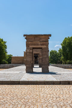 View of ancient stone doorway standing proudly on geometric paving under a vibrant blue sky, a portal to history in Temple of Debod, Comunidad de Madrid, Spain.