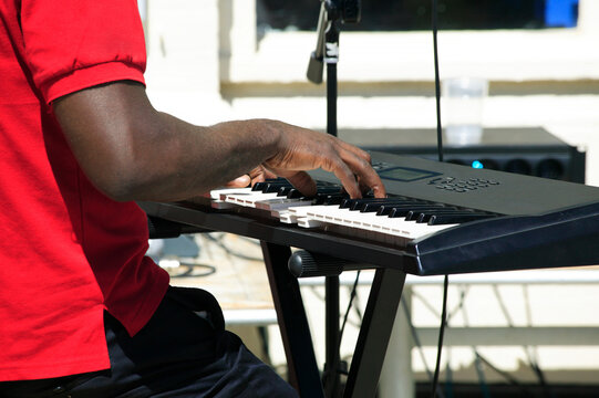 Afro musician playing a synthesizer electric keyboard piano at a live concert, music performance stock photo image