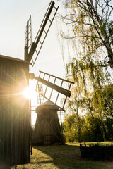 Old vintage wooden wind mills in a backlight in a  Museum of Folk Life and Architecture of Middle Naddnipryanshyna in  Pereyaslav-Khmelnytsky, Ukraine.