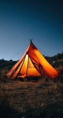Glowing, pointed tent sits in a field at night under a starry sky, light emanating from within