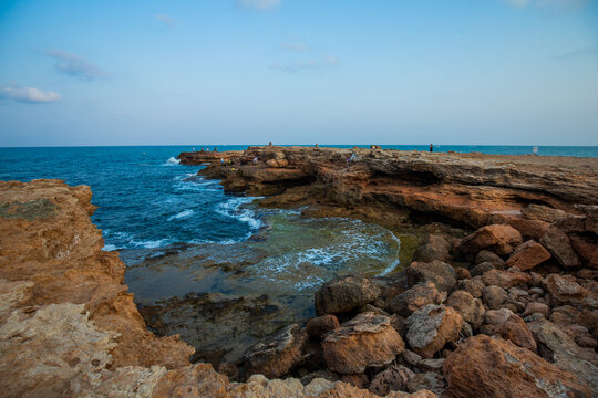 A coastal view of Cala de la Zorra in Torrevieja, Spain, featuring rugged rocky cliffs and clear turquoise Mediterranean waters. The image captures the natural beauty of the Costa Blanca shoreline