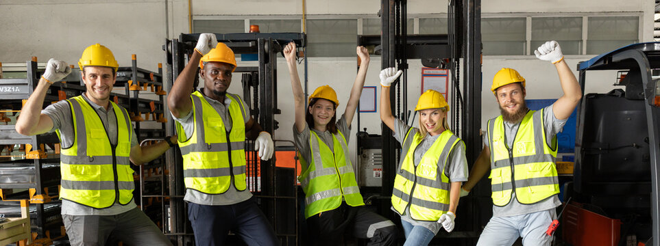 Diverse group of warehouse workers in safety gear raising fists in celebration, showing unity, motivation, and success in industrial teamwork. Perfect for logistics and labor force concepts. - Powered by Adobe