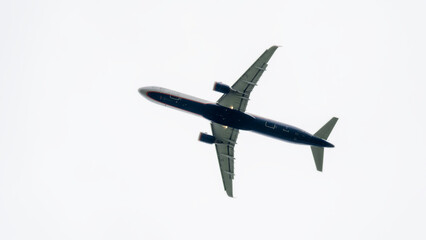 A large jet plane is flying through the sky. The plane is black and white, and it is the only object visible in the image. The sky is clear and empty, with no clouds or other objects in the background