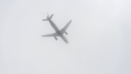 A plane is flying through a cloudy sky. The sky is overcast and the plane is low to the ground