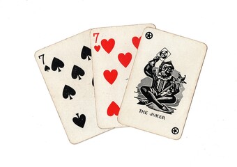 A hand of vintage playing cards showing a joker and two cards of the same value isolated on a white background.