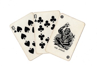 A hand of vintage playing cards showing a joker and two cards of the same value isolated on a white background.