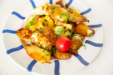 Baked potato with egg, cheese and sausage on white plate with blue stripe on white.