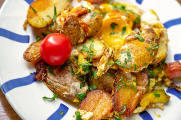 Baked potato with egg, cheese and sausage on part of blue striped plate.