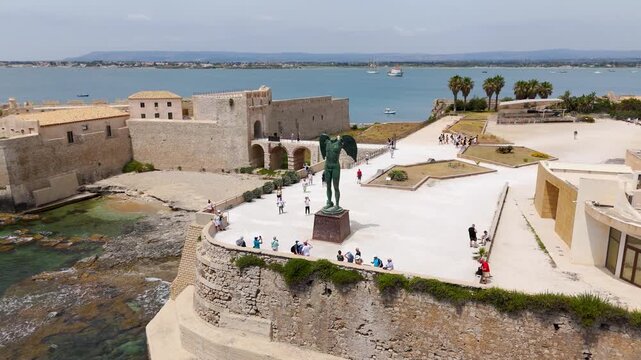 Aerial Drone Shot Circling The Mitoraj Sculpture On Ortigia Island, Syracuse, Sicily, Italy On A Bright Summer Day.