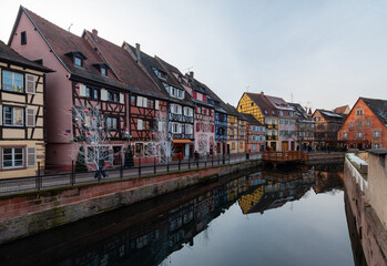 Fototapeta premium Row of colorful half-timbered houses along a canal in Colmar, Alsace, France. The photograph highlights the traditional Alsatian architecture, vibrant facades, and charming waterway setting 