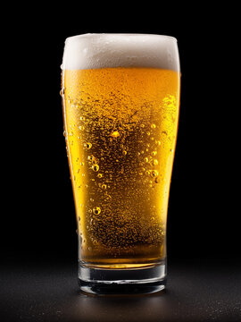 Golden beer with float in the glass in black background. Close up shot.	