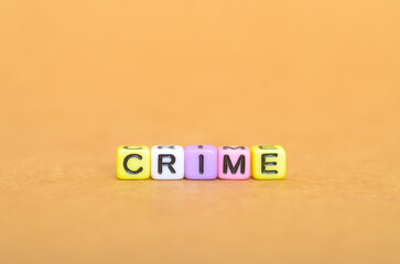 CRIME spelled with colorful letter beads on light brown background — law violation concept