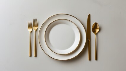 A sophisticated table setting displays elegant white plates with gold-rimmed edges, alongside matching gold cutlery, creating a refined and inviting aesthetic.