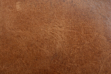 A close-up, full-frame shot of a rich brown distressed leather surface, showcasing its aged and rustic texture