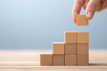 Obraz premium A hand places a wooden block atop a stack of blocks arranged in ascending order, symbolizing growth and progress