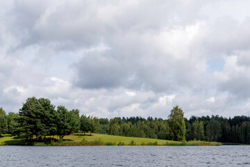 Serene Lake with Green Shoreline and Cloudy Sky