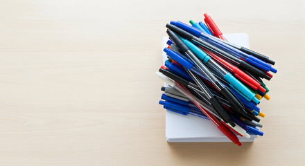 Obraz premium A pile of colorful pens on a stack of white paper