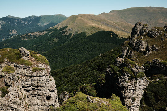 Rocky cliffs and green slopes of Stara Planina with mountain ridges in the distance. Babin Zub mount in summer season. Serbia country