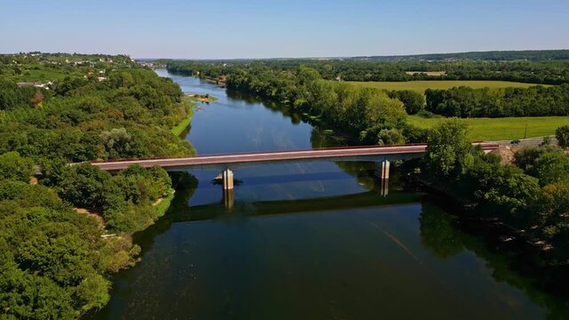 Drone top view of the Vienne River with Pont aval de Chinon bridge crossing through green forest and countryside fields, Chinon, Indre-et-Loire, France.