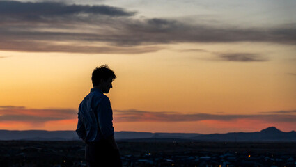 Fototapeta premium A man is standing proudly on top of a beautiful hill at sunset