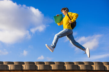 College student running and jumping with headphones and backpack