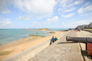 Un couple marche sur les remparts de Saint Malo en Bretagne, face à la piscine de mer de bon secours et a l'ile du grand Bé