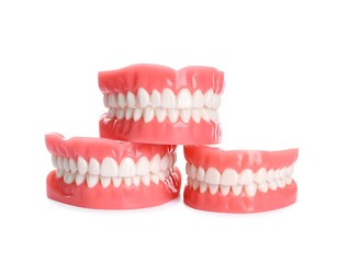 Obraz premium Three pink plastic dentures stacked on a white background