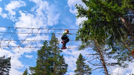 outdoor activity with child crossing rope net in adventure park