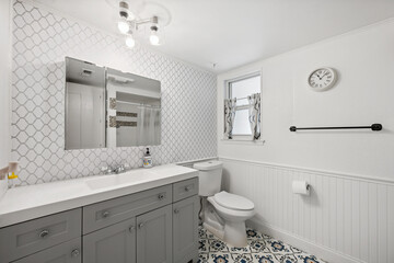 A bathroom featuring a sink, toilet, mirror, and a clock on the wall
