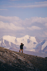 a man alone on a mountainside overlooking snow-covered mountains
