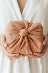 Hands hold fabric wrapped package. Brown textile gift idea. Sustainable living with reusable material. Zero waste lifestyle.