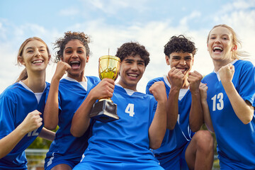 Young football team holding trophy after victory