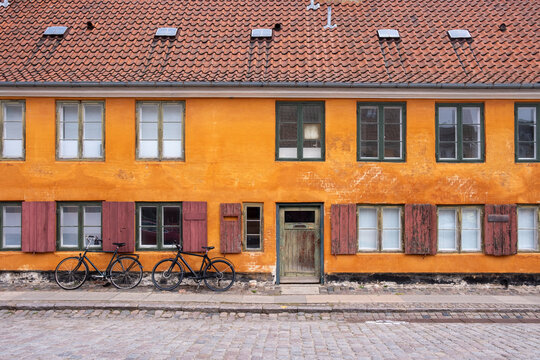 Row of ochre houses with bicycles in Nyboder Copenhagen Denmark, historic quarter reflecting cultural identity, urban lifestyle, cycling tradition and architectural heritage