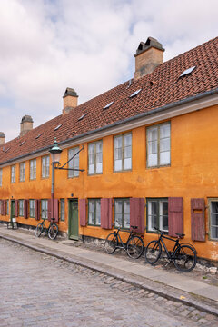 Perspective of ochre houses with bicycles in Nyboder Copenhagen Denmark, historic architecture, cultural heritage, cycling culture and sustainable urban identity