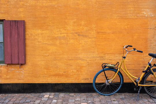 Minimalist scene with bicycle against ochre wall in Nyboder Copenhagen Denmark, representing urban identity, historic heritage, cycling tradition and architectural charm