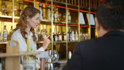 Smiling bartender serving drinks to customers at a modern bar