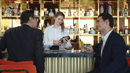 Smiling bartender serving drinks to customers at a modern bar