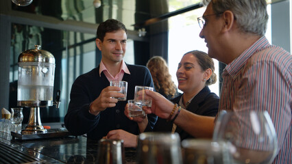 Smiling bartender serving drinks to customers at a modern bar