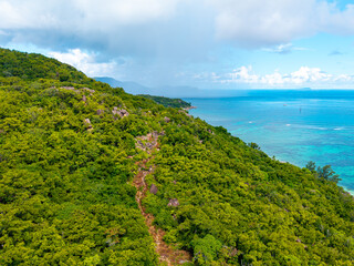 Aerial view of Praslin Island, Seychelles, featuring lush green hills, tropical coastline, and calm...