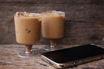 Smartphone and iced coffee on wood background