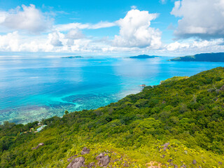 Aerial view of Praslin Island, Seychelles, featuring lush green hills, tropical coastline, and calm...