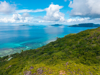 Aerial view of Praslin Island, Seychelles, featuring lush green hills, tropical coastline, and calm...