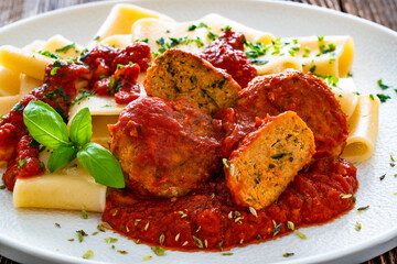 Pasta with meatballs in bolognese sauce on wooden table	